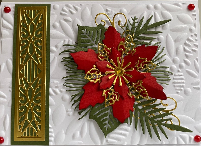 May include: A Christmas card with a red poinsettia flower, gold accents, and green foliage on a white background.