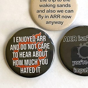 May include: Three round buttons with different messages. The first button is black with white text and a red graphic that says "I enjoyed ARR and do not care to hear about how much you hated it". The second button is beige with black text that says "I actually enjoy the trip to the waking sands and also we can fly in ARR now anyway". The third button is black with white text and a gray graphic that says "ARR isn't bad you're just impatient".