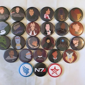 Może przedstawiać: Kolekcja 21 okrągłych guzików z postaciami i logo z serii gier wideo Mass Effect. Guziki są ułożone w okrągły wzór z logo N7 w środku.