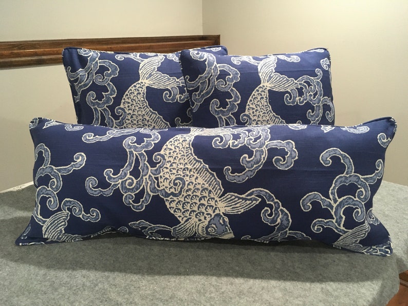 May include: Three decorative throw pillows with a blue background and white fish and cloud pattern. The pillows are made of a soft, textured fabric.