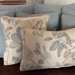 May include: A group of decorative throw pillows in a variety of patterns and colors. The pillows are arranged on a brown couch. The pillows are made of a soft, comfortable fabric and feature a variety of designs, including floral patterns and solid colors.