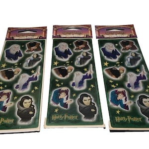 May include: Three sticker sheets featuring characters from the Harry Potter series. Each sheet has a green background with character illustrations and gold stars. The top of each sheet has the words "Harry Potter Stickers".