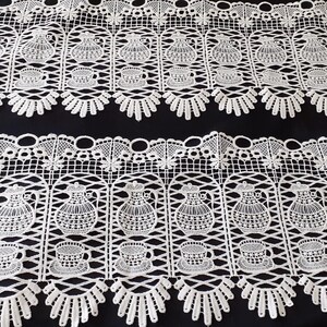 May include: Two strips of white lace trim featuring a repeating pattern of teapots and teacups arranged within arched columns. The lace has a scalloped bottom edge and a decorative openwork border along the top, creating a detailed textile design.