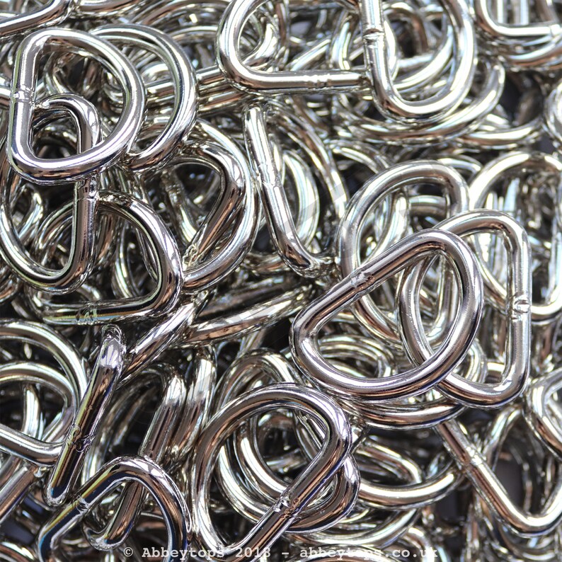May include: A pile of silver metal D-rings. The rings are all the same size and shape, and they are arranged in a random pattern.
