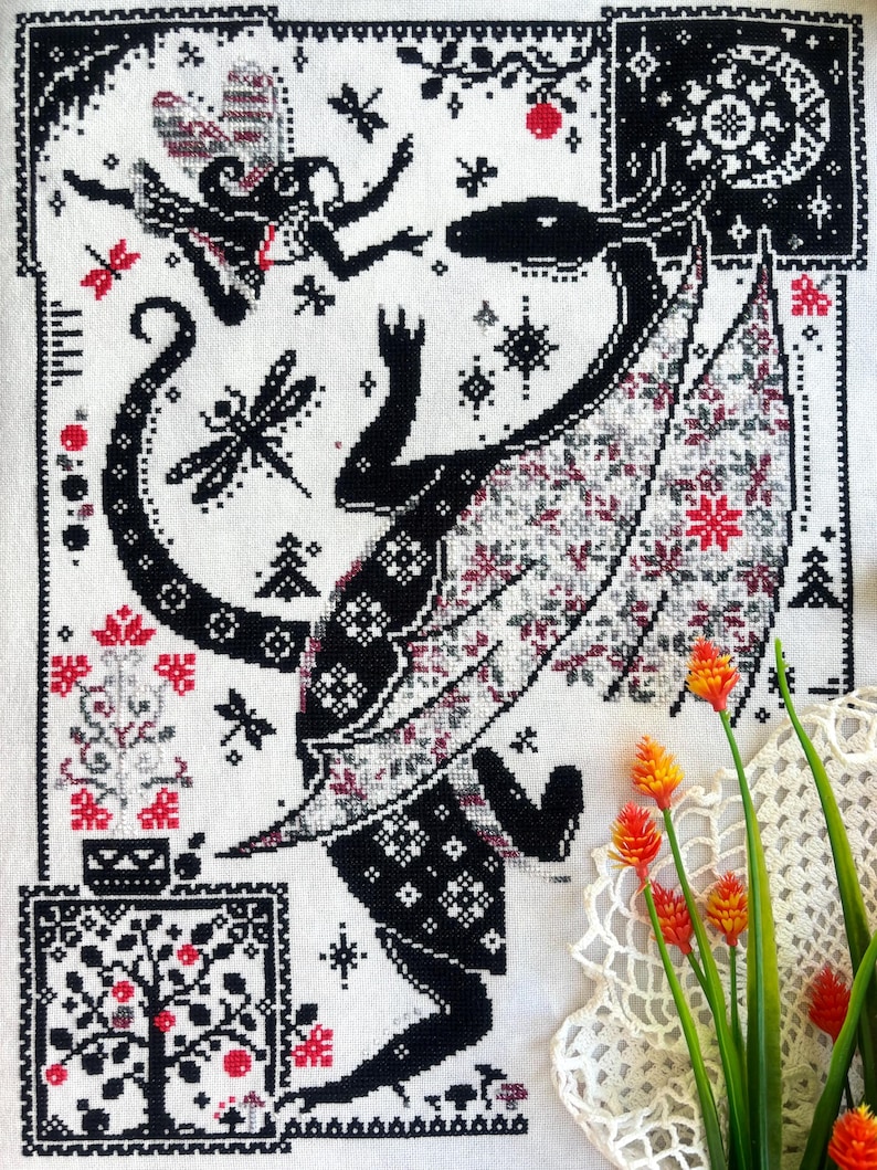 May include: A cross-stitch embroidery on white fabric featuring a large black dragon with patterned wings, a small fairy, dragonflies, and floral motifs. The design uses a black, white, and red color palette with intricate geometric borders.