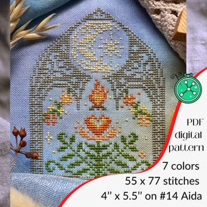 May include: A cross-stitch design on pale blue fabric, depicting a floral arrangement with a moon and star. The pattern includes the text "PDF digital pattern", "7 colours", and measurements of 10.16cm x 13.97cm on #14 Aida.