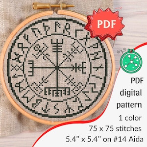 以下が含まれることがあります： 木製の刺繍枠に収められた、濃い緑色のシンボルと中心のコンパスのような要素で構成された円形デザインのクロスステッチパターン。 画像には赤い「PDF」タグと詳細が含まれています：13.7 cm x 13.7 cm、#14アイーダ。