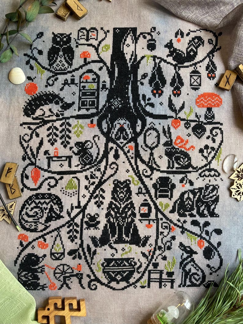May include: Cross-stitch pattern featuring a stylized tree with black branches and a variety of woodland creatures and objects. The design includes an owl, squirrel, bats, bear, rabbit, and other animals, with accents of orange and green on a light gray background.
