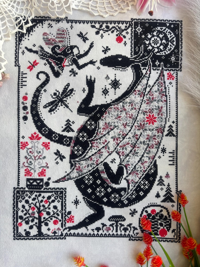 May include: A cross-stitch embroidery on white fabric featuring a large black dragon with patterned wings, a small fairy, dragonflies, and trees. The design uses black, white, and red thread to depict a forest scene with stars and mushrooms.