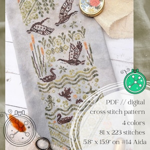 May include: A cross stitch pattern on light gray fabric featuring ducks, cattails, and water motifs in brown, green, and orange. Text reads: PDF // digital cross stitch pattern, 4 colors, 81 x 223 stitches, 5.8" x 15.9" on #14 Aida.