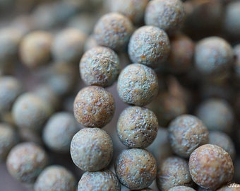 May include: A close-up of a strand of light blue and brown beads. The beads have a rough, textured surface.