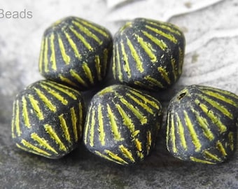 May include: Five black and yellow glass beads with a geometric design. The beads are cube shaped with a raised pattern of yellow lines.