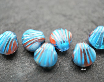 May include: Six blue and orange glass beads shaped like seashells. The beads have a white swirl pattern.