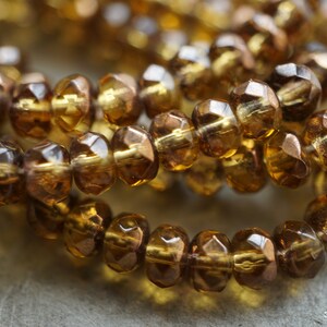 May include: A strand of amber glass beads with a faceted finish. The beads are strung together on a clear thread.