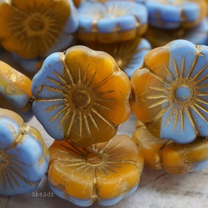 May include: A strand of glass beads in shades of blue and amber. Each bead is shaped like a flower with a raised center and a gold-toned rim.