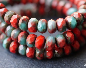 May include: Close-up of a strand of red and green faceted glass beads. The beads are arranged in a circular pattern and have a mottled, marbled appearance.