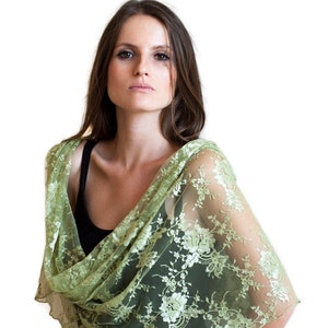 May include: A green lace shawl with floral embroidery. The shawl is draped over a person's shoulders and is made of a delicate, sheer fabric.
