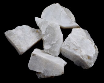 May include: A group of five white, opaque, rough-hewn, natural mineral stones. The stones are various sizes and shapes, and have a slightly iridescent sheen.