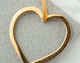 May include: Gold heart-shaped pendant with the inscription "Dad, I carry you in my heart x".