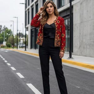 May include: A red jacket with gold and black embroidery, paired with a black top and pants. The jacket features an intricate floral design. The outfit is completed with black heels. The ensemble is suitable for formal or semi-formal occasions.