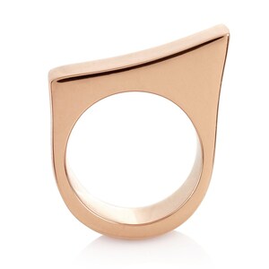 May include: A rose gold ring with a unique, angular design. The ring is made of a smooth, polished metal and has a simple, modern aesthetic.