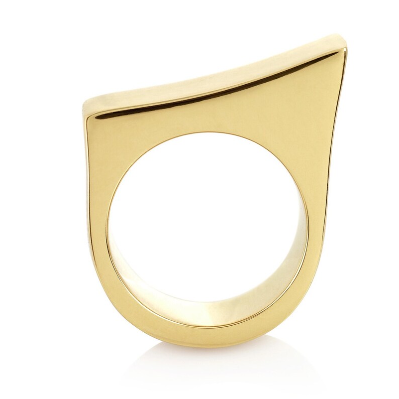 May include: A gold-colored ring with a unique, angular design. The ring is made of a smooth, polished metal and has a simple, modern aesthetic.