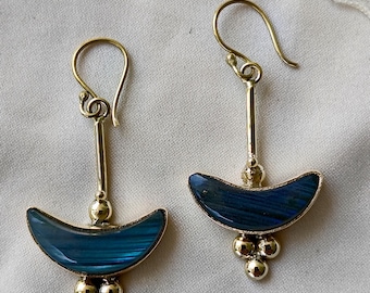 May include: A pair of gold-toned earrings with a crescent-shaped, blue-green stone inlay. The earrings have a long, slender post with a small ball accent and three smaller balls at the bottom. The hooks are curved.