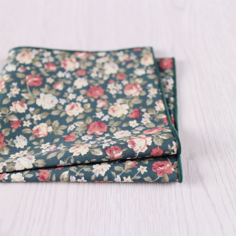 May include: A folded green and pink floral patterned pocket square with a dark green border.