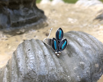 May include: A silver ring with turquoise stones set in a leaf design.