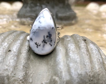 May include: A silver ring with a teardrop-shaped white and black dendritic opal stone.