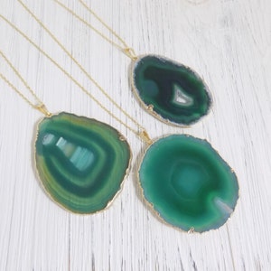 May include: Three gold chain necklaces with green agate pendant stones. The pendants are different shapes and sizes, with a variety of green shades.