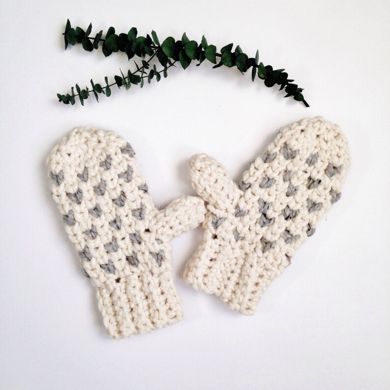 May include: A pair of crocheted mittens in white with gray accents. The mittens have a textured pattern and are perfect for keeping your hands warm in the winter.