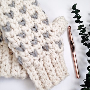 May include: A pair of white and gray crocheted fingerless gloves with a rose gold crochet hook.