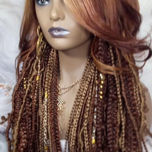 May include: A long, wavy wig with brown and blonde ombre hair. The wig has small braids with gold beads throughout the hair. The wig is styled with a side part and a long, flowing fringe.
