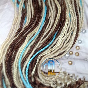 May include: A bundle of synthetic hair extensions in brown, blonde, and turquoise colors. The hair is long and straight, and the strands are arranged in a loose braid.