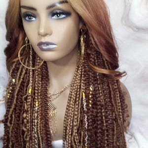 May include: A long, blonde wig with brown and blonde braids. The wig is styled with beads and gold accents.