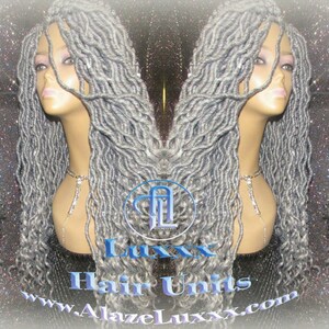 May include: A silver grey long, wavy synthetic hair wig on a mannequin head. The wig is styled in a loose, flowing style. The wig is on a white background with silver glitter.
