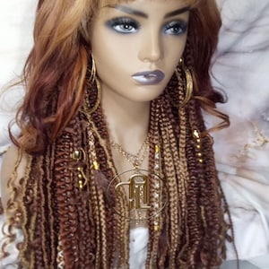May include: A long, brown and blonde wig with a fringe. The wig is styled with braids and beads.