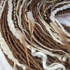 May include: Brown and white synthetic dreadlocks with brown feathers and beads.