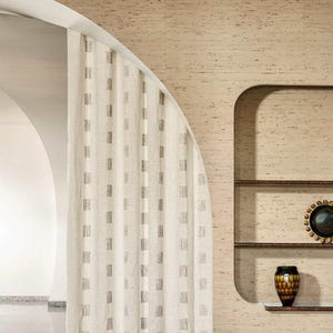 Könnte beinhalten: Gemütliches Wohnzimmer mit zwei gepolsterten Sesseln, einem goldenen Beistelltisch und einem Einbauregal mit dekorativen Gegenständen. Der Raum hat eine neutrale Farbpalette mit strukturierter Wand und gemustertem Teppich.