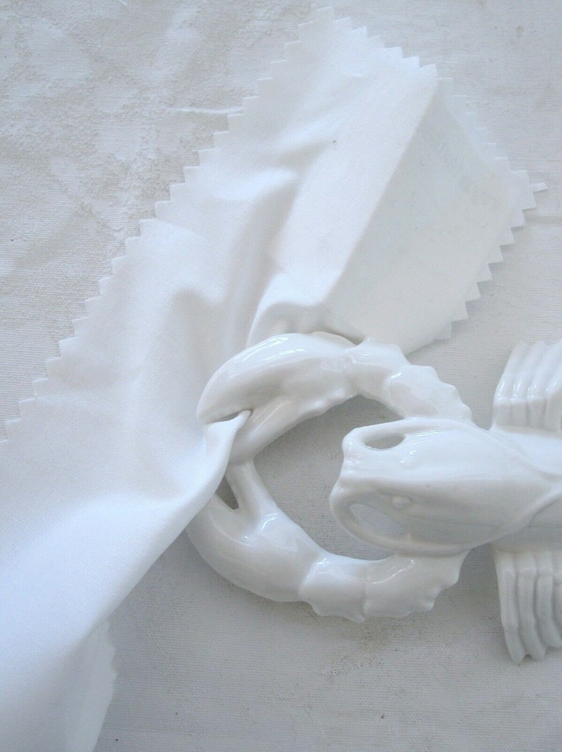 Peut inclure: Figurines de homard en porcelaine blanche avec un design d&eacute;taill&eacute;. Le homard est enroul&eacute; en cercle, les pinces crois&eacute;es sur le corps.