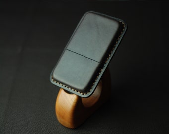 May include: A black leather phone case with a stitched edge and a wooden stand.