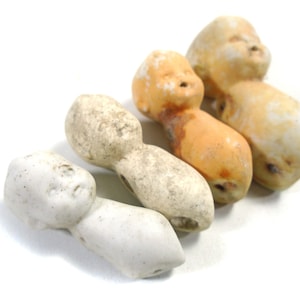 May include: Five vintage porcelain doll heads with painted facial features. The heads are attached to small, elongated bodies. The doll heads are in various shades of white, cream, and orange.