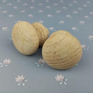 以下が含まれることがあります： 溝の入ったデザインのウッドノブが2つ。ノブは薄い茶色で丸みを帯びています。