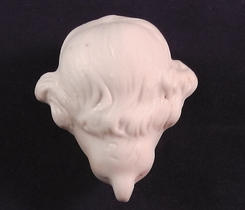 May include: White porcelain doll head with detailed hair sculpted in a side part style.