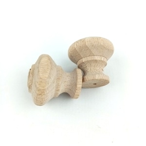Può includere: Due pomelli in legno non finiti con una parte superiore arrotondata e una base cilindrica. I pomelli sono in legno marrone chiaro e hanno una finitura liscia.