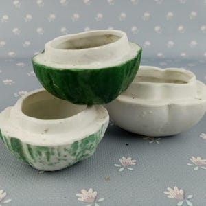 Könnte beinhalten: Drei Keramikbehälter in Wassermelonenform. Die Behälter sind weiß mit grünen Akzenten und haben eine glänzende Oberfläche.