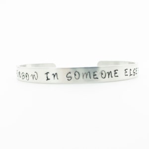 Op de afbeelding: Zilveren armband met de inscriptie "Vind de regenboog in de wolk van iemand anders".