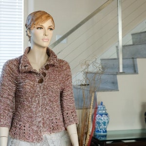 May include: A brown and white knitted cardigan with a button closure. The cardigan has a collar and long sleeves. The cardigan is being modeled by a mannequin.