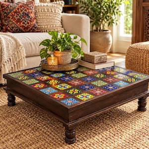 Puede incluir: Una mesa de centro cuadrada de madera con acabado marrón oscuro y cuatro patas torneadas. El tablero está incrustado con una cuadrícula de azulejos de cerámica coloridos y estampados en tonos azul, amarillo, rojo y verde, creando una superficie de mosaico.
